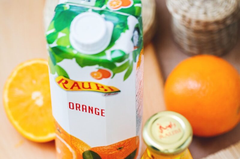 orange juice in glass beside container